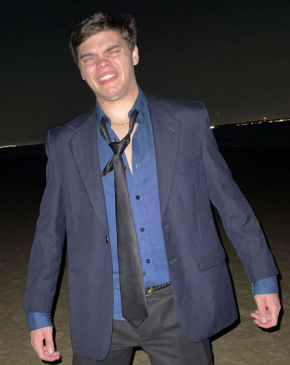 Treverse standing on a beach in a raggedy suit.